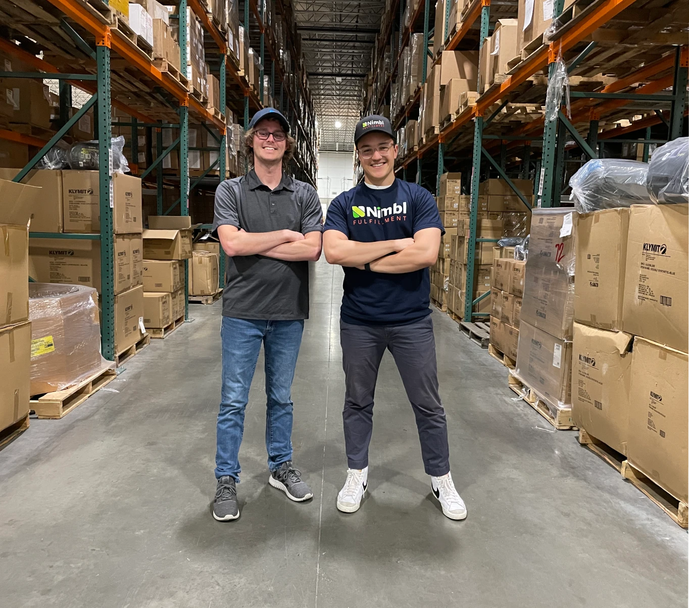 Two people in a warehouse, smiling at the camera